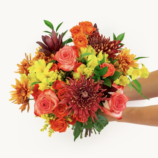 Vibrant floral bouquet featuring roses, lilies, and chrysanthemums in warm autumn tones.