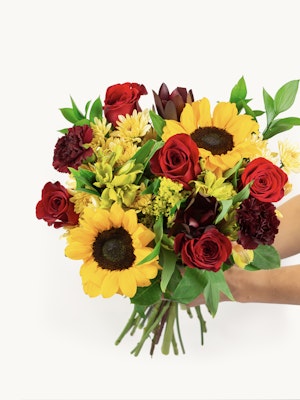 Vibrant mixed flower bouquet featuring sunflowers, red roses, and greenery, perfect for gifts.