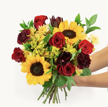 Vibrant mixed flower bouquet featuring sunflowers, red roses, and greenery, perfect for gifts.