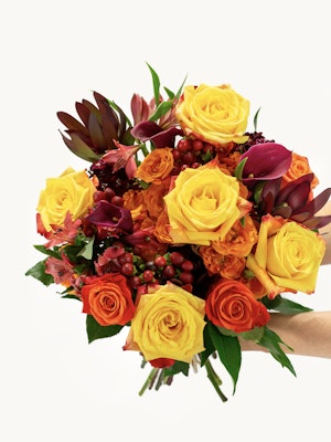 Vibrant bouquet of yellow and orange roses mixed with lush greenery, perfect for celebrations.