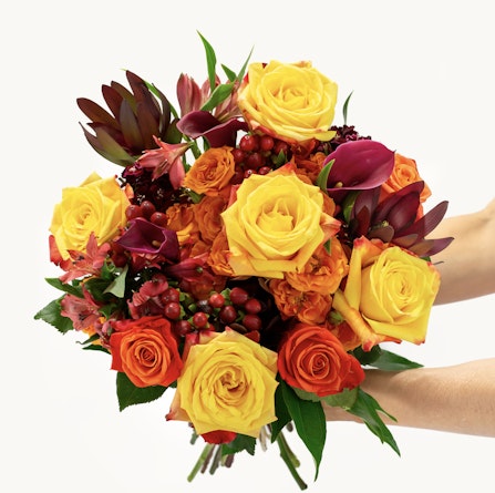 Vibrant bouquet of yellow and orange roses mixed with lush greenery, perfect for celebrations.