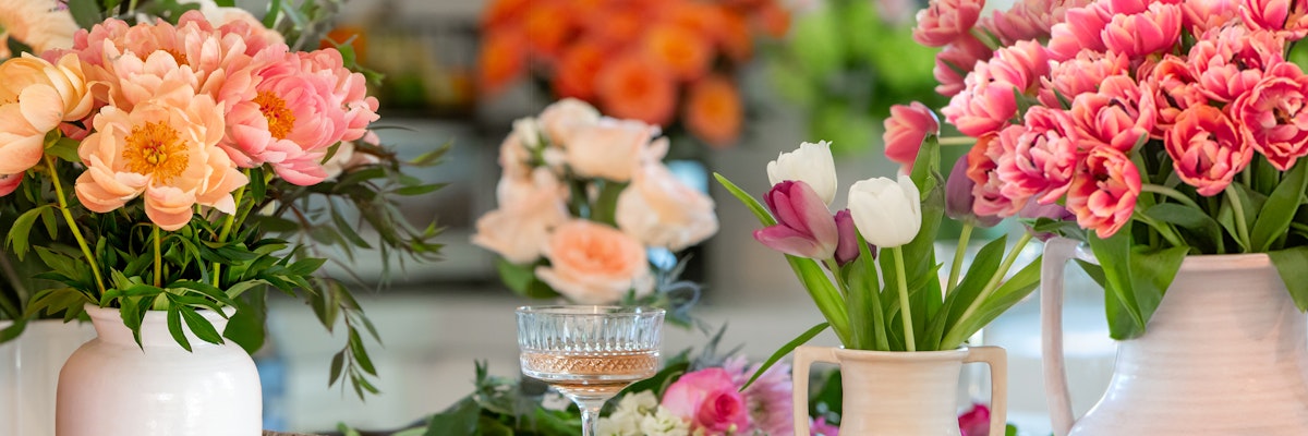 A vibrant floral display featuring tulips, peonies, and roses in elegant vases.