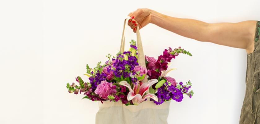 Vibrant floral arrangement with purple lilies and pink roses in a stylish tote bag.