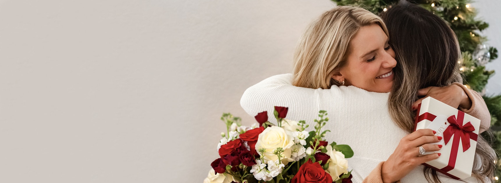 A joyful embrace between two friends, surrounded by a beautiful flower bouquet and a gift.