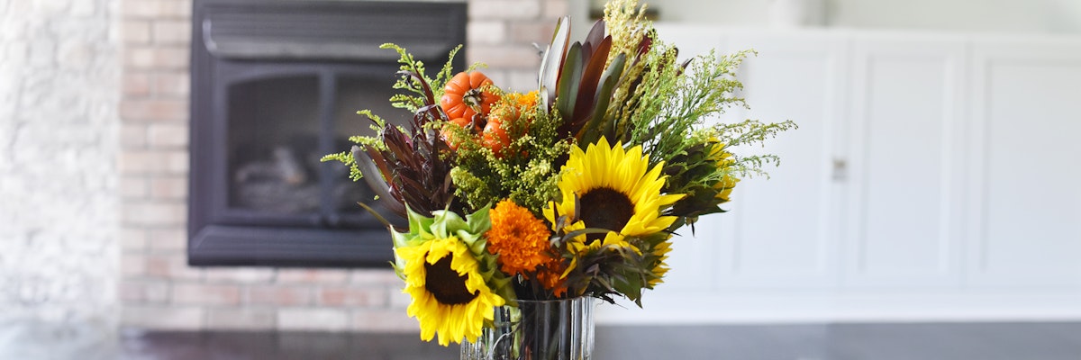 Vibrant sunflower bouquet featuring marigolds and greenery, perfect for autumn decor.