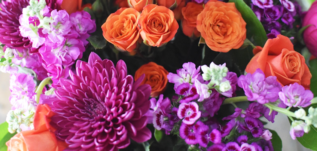 Vibrant floral bouquet featuring orange roses and purple chrysanthemums for a cheerful display.