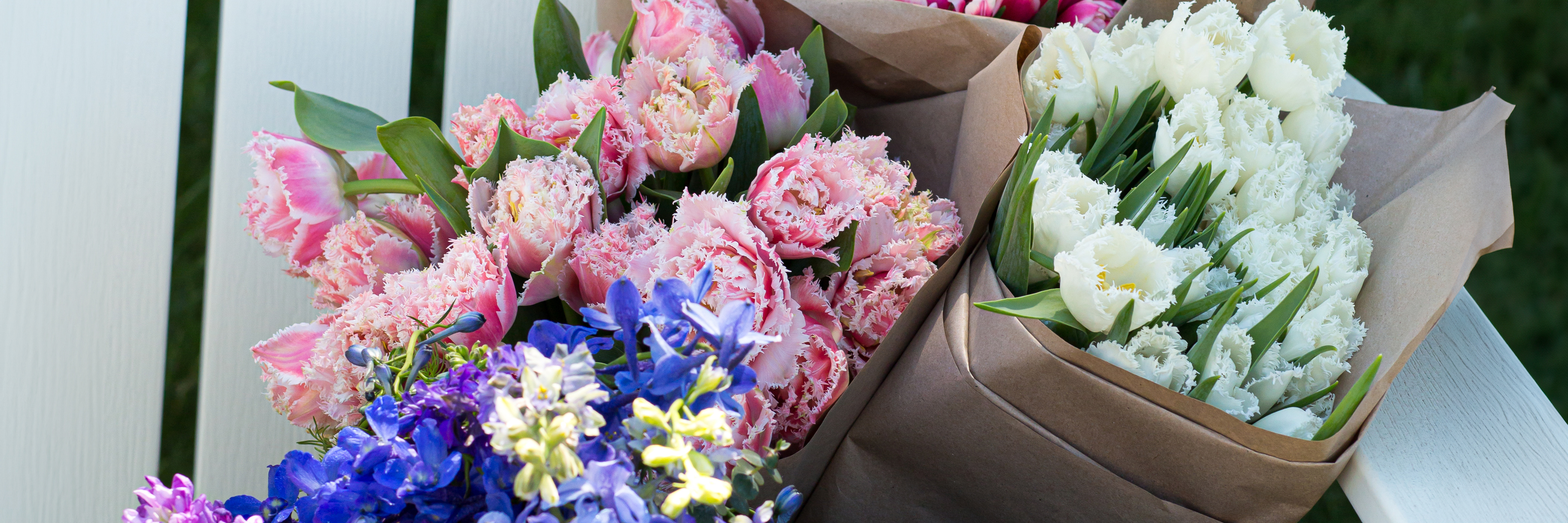 Vibrant spring flowers in pink, white, and purple hues, elegantly packaged in rustic boxes.