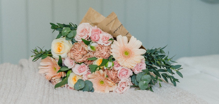Soft pastel floral bouquet featuring pink gerbera daisies, roses, and greenery.
