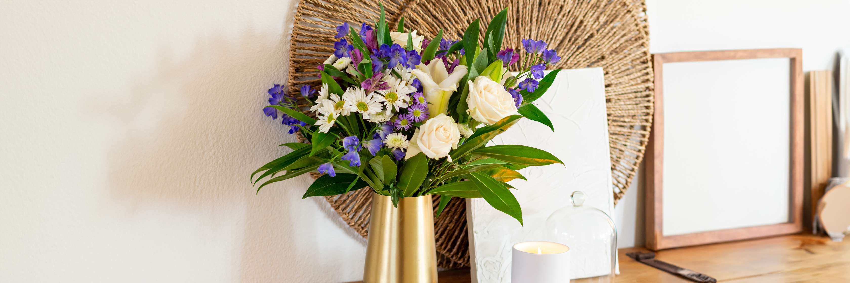 Charming floral arrangement featuring white roses and purple blooms in a stylish gold vase.