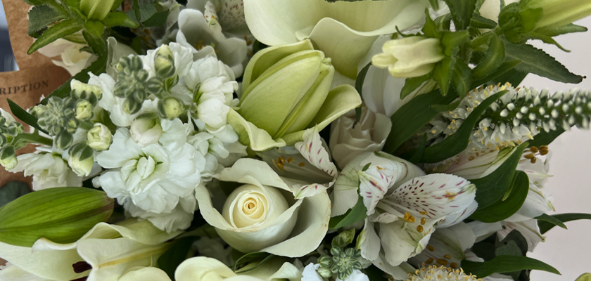 Elegant white floral arrangement featuring roses, tulips, and greenery, perfect for any occasion.