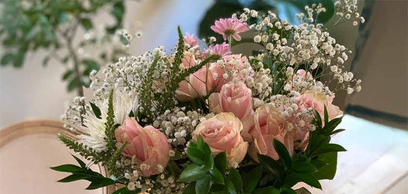 Delicate arrangement of pink roses, daisies, and baby's breath in a lush bouquet.