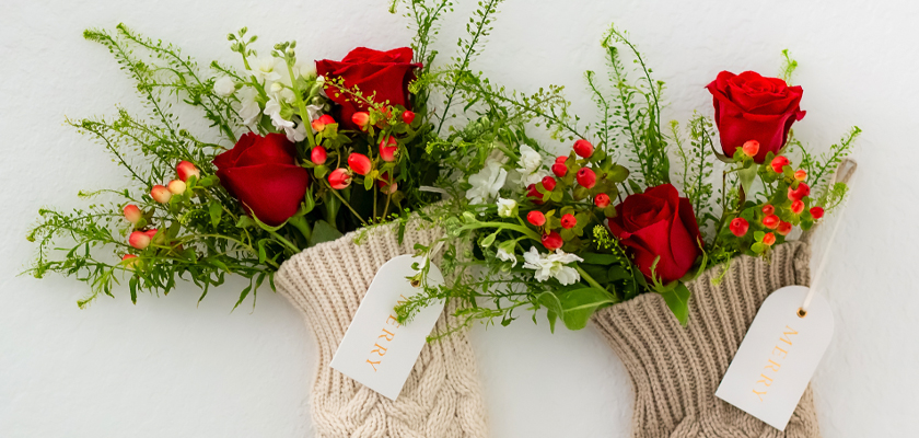 Festive holiday stockings filled with red roses and greenery, perfect for cheerful decorations.