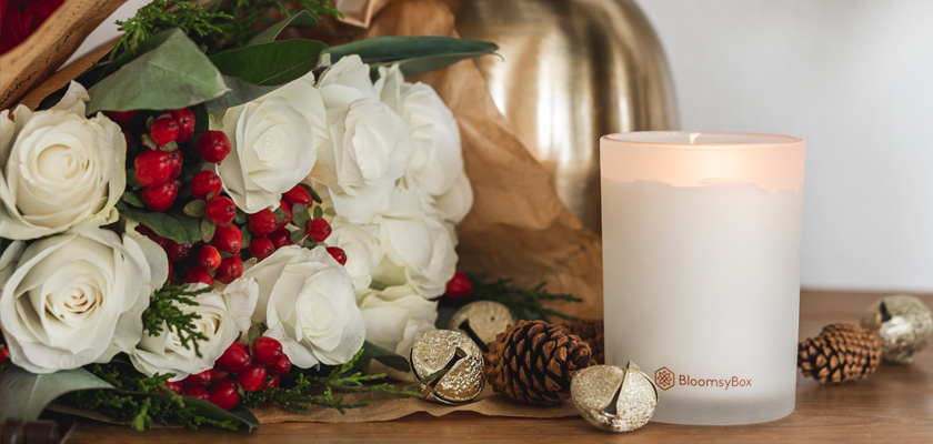 Elegant white rose bouquet with red berries and a decorative candle, perfect for special occasions.