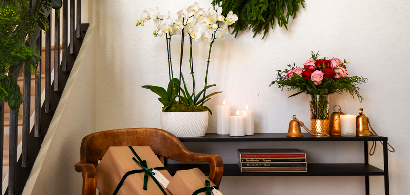 A stylish home decor scene featuring orchids, candles, and a beautiful floral arrangement.