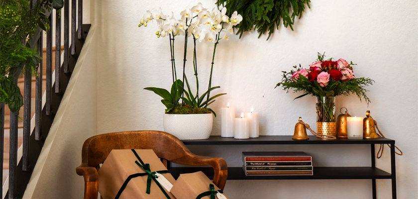 A stylish home decor scene featuring orchids, candles, and a beautiful floral arrangement.