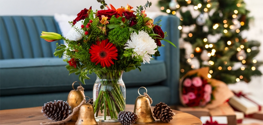 Festive floral arrangement featuring red and white blooms, with holiday decor in the background.