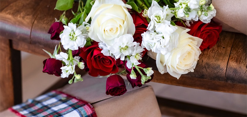 Charming floral arrangement featuring red and white roses with delicate greenery, ideal for gifts.