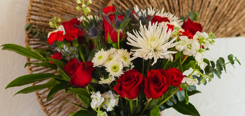 Vibrant bouquet featuring red roses, white chrysanthemums, and lush greenery in elegant arrangement.