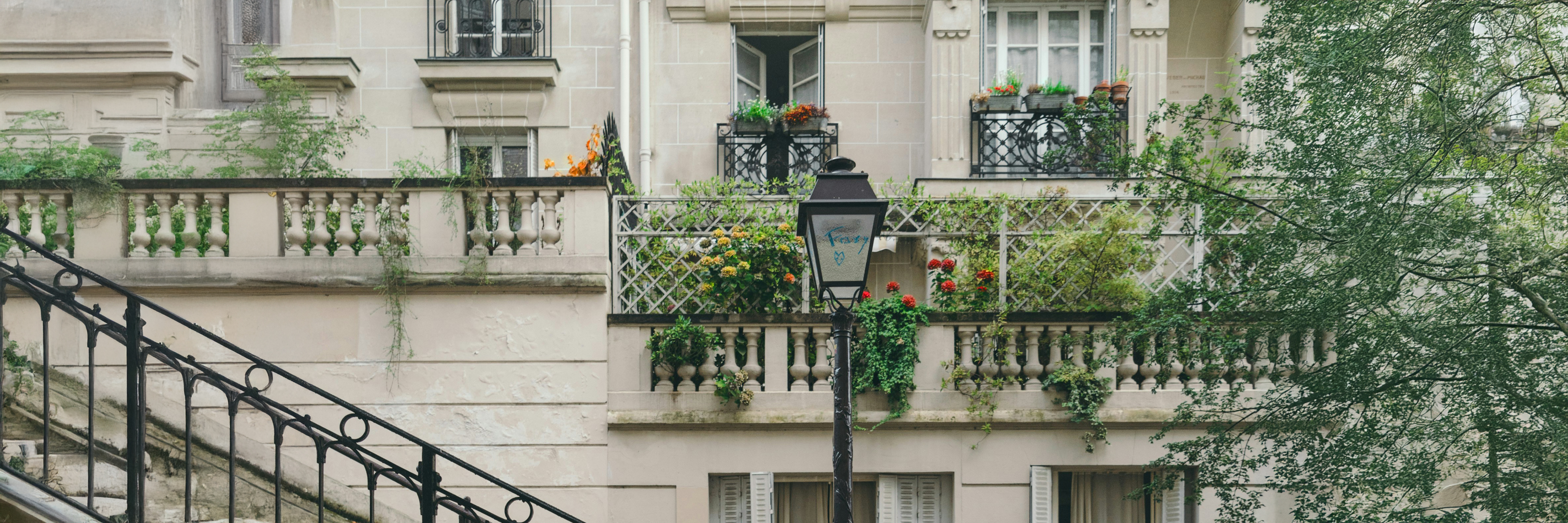 Charming Parisian apartment building adorned with vibrant flower boxes and lush greenery.