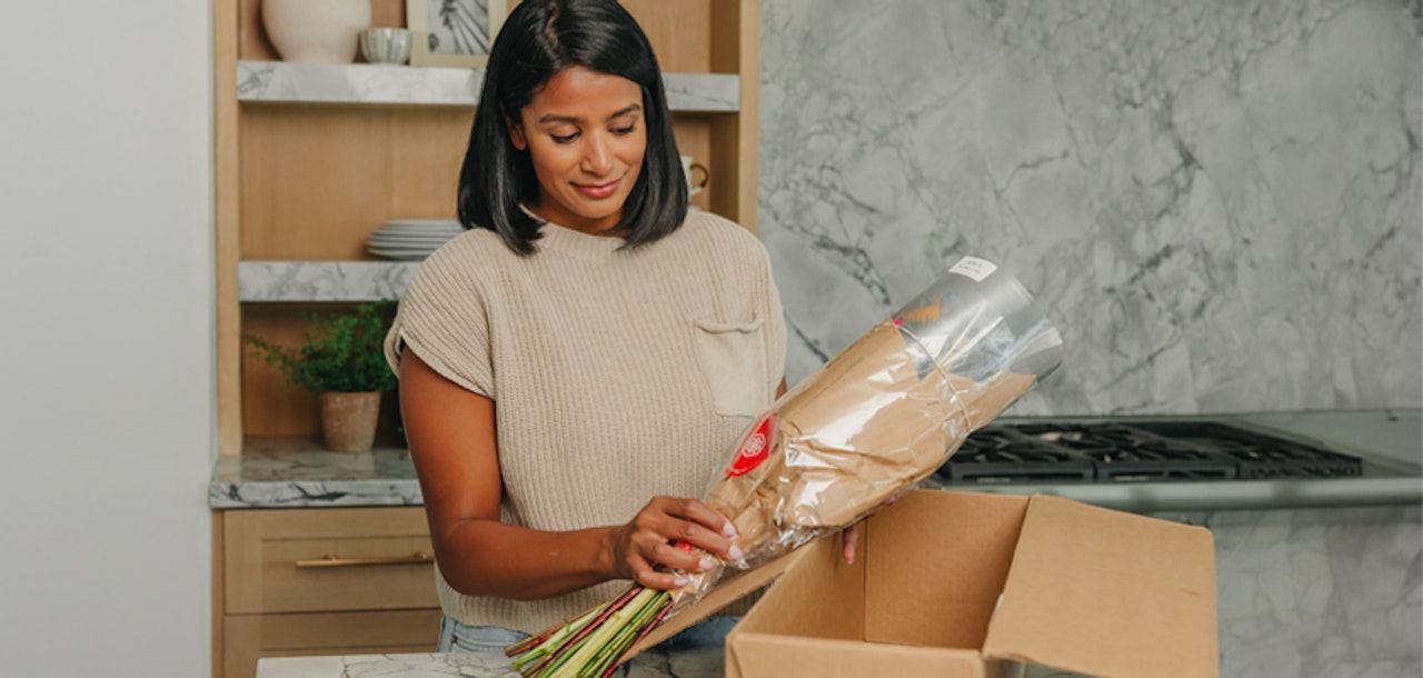 A woman unboxing fresh flowers in a stylish kitchen, excited to arrange her new blooms.