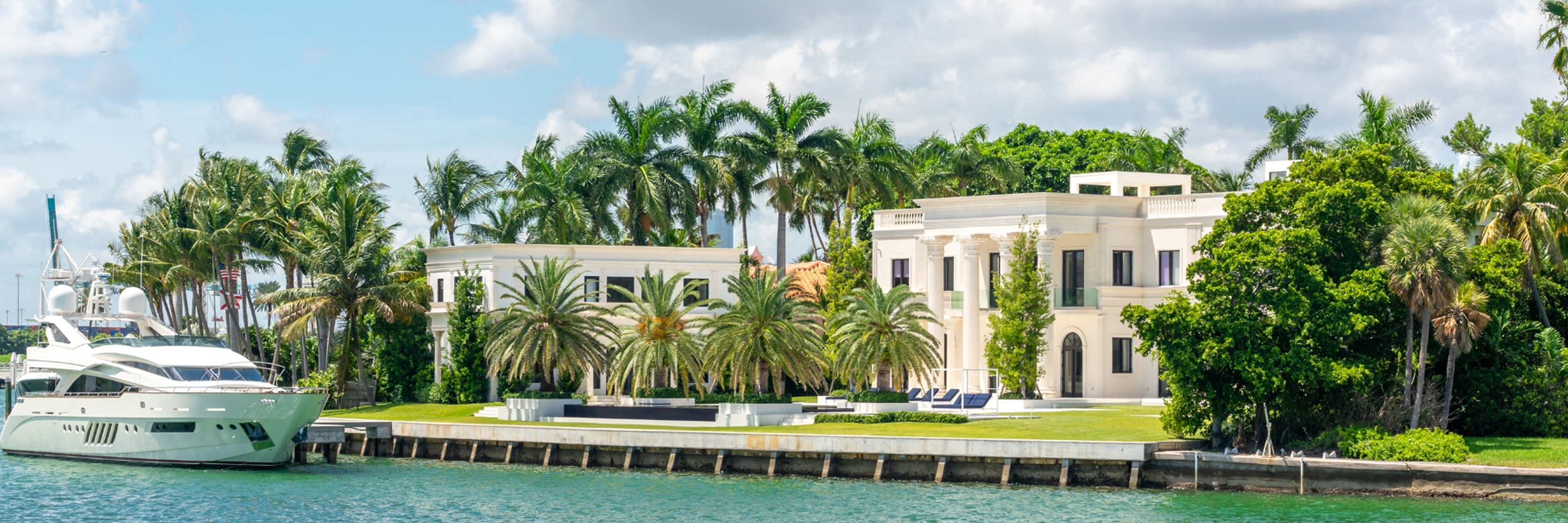 Luxurious waterfront mansion surrounded by palm trees and a sleek yacht. A tropical paradise escape.