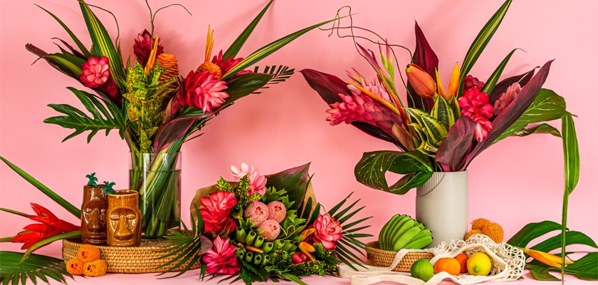 Vibrant tropical floral arrangements with colorful blooms and greenery against a chic pink backdrop.