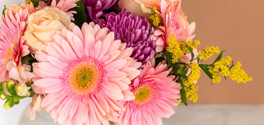 Vibrant floral arrangement featuring pink gerbera daisies, roses, and yellow blooms.