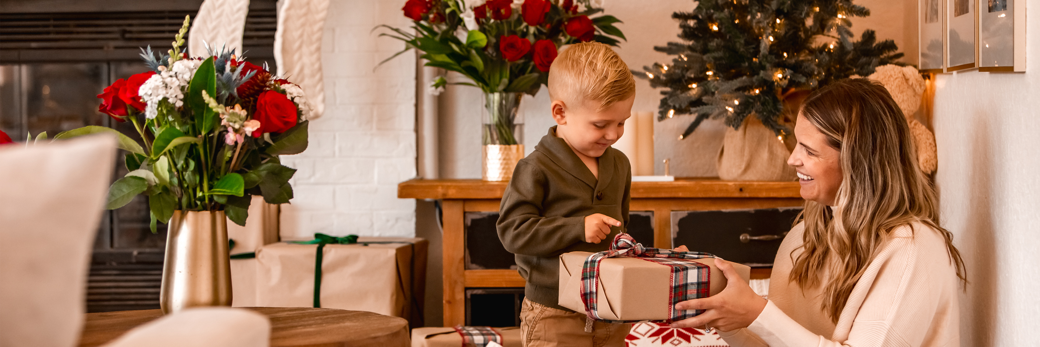 A joyful scene of a child presenting a gift to a smiling mother in a festive setting.