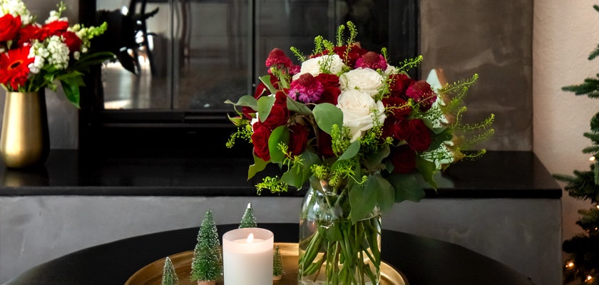 Elegant floral arrangement with red and white blooms in a glass vase, set on a stylish coffee table.