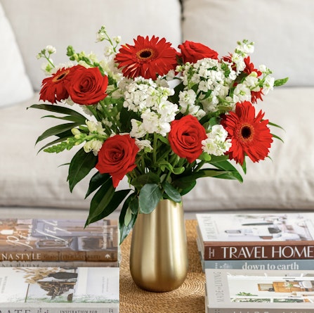 Vibrant arrangement of red roses and white flowers in a gold vase, enhancing home decor.