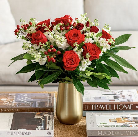 Vibrant red roses and white blooms in a chic vase, surrounded by stylish coffee table books.