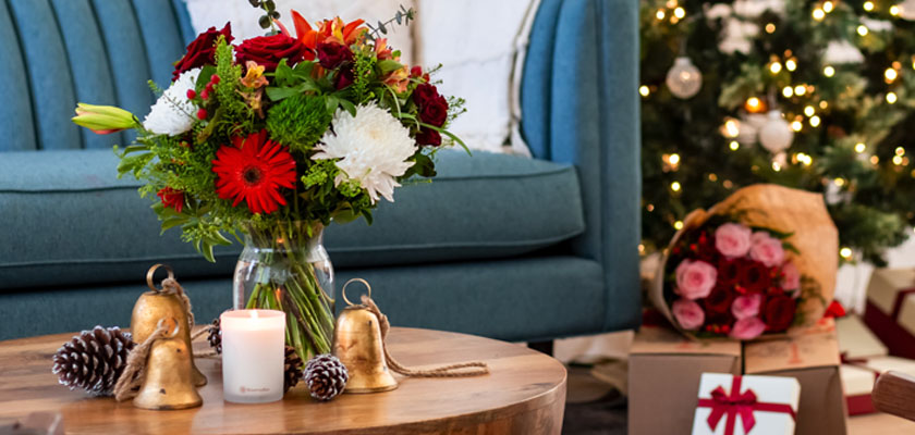 Festive floral arrangement with red and white blooms, complemented by holiday decor and presents.