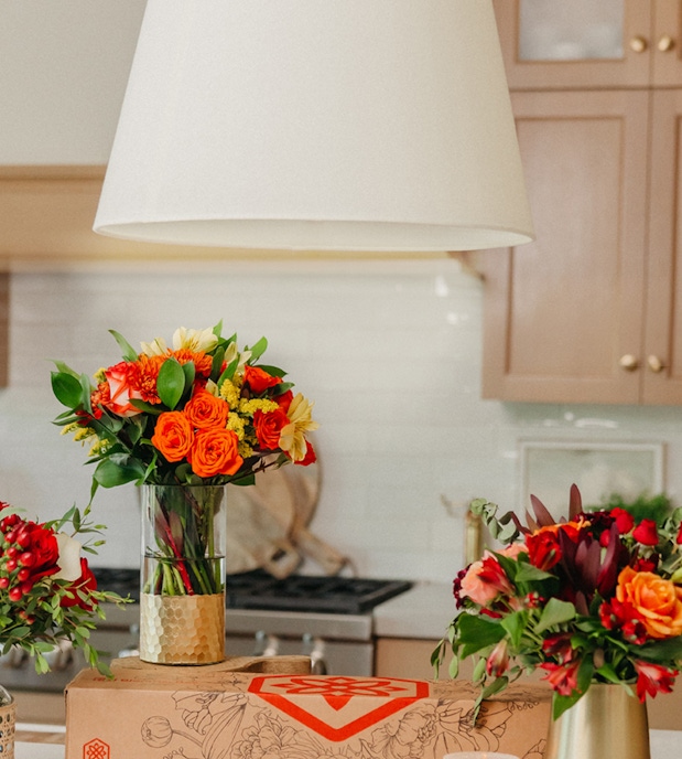 Vibrant floral arrangements featuring roses, daisies, and greenery in a stylish kitchen setting.