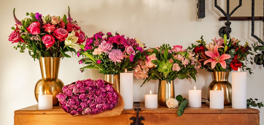 Vibrant floral arrangements in golden vases, surrounded by glowing candles, create a warm ambiance.