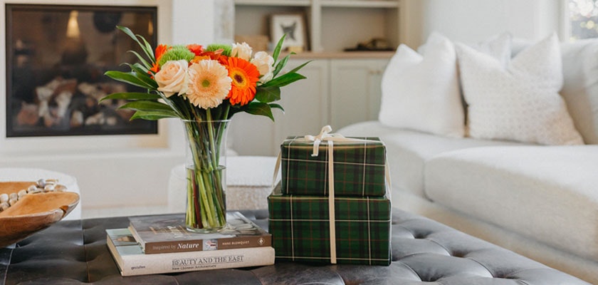 A vibrant floral arrangement in a vase alongside beautifully wrapped gift boxes on a coffee table.
