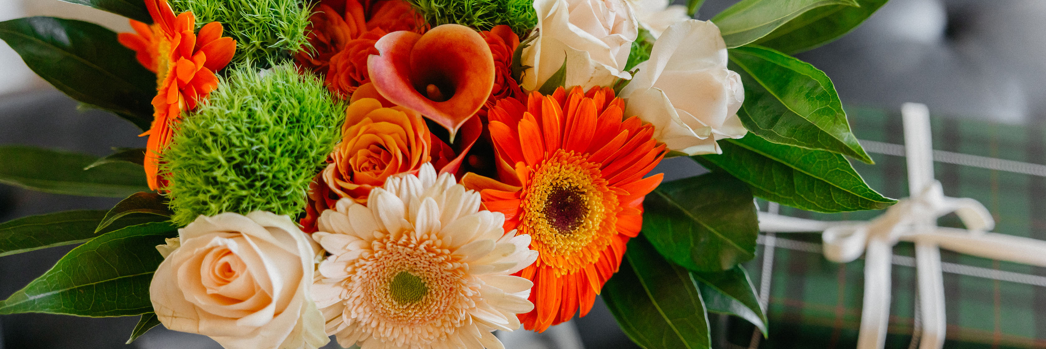 Vibrant bouquet featuring orange gerbera daisies and lively green accents, perfect for celebrations.