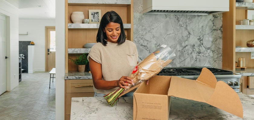 Woman unboxing a fresh flower delivery in a modern kitchen, showcasing vibrant blooms.