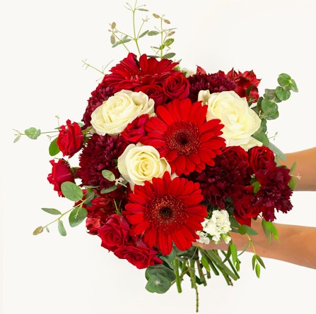 Vibrant bouquet featuring red gerberas, roses, and white blooms, ideal for celebrations.