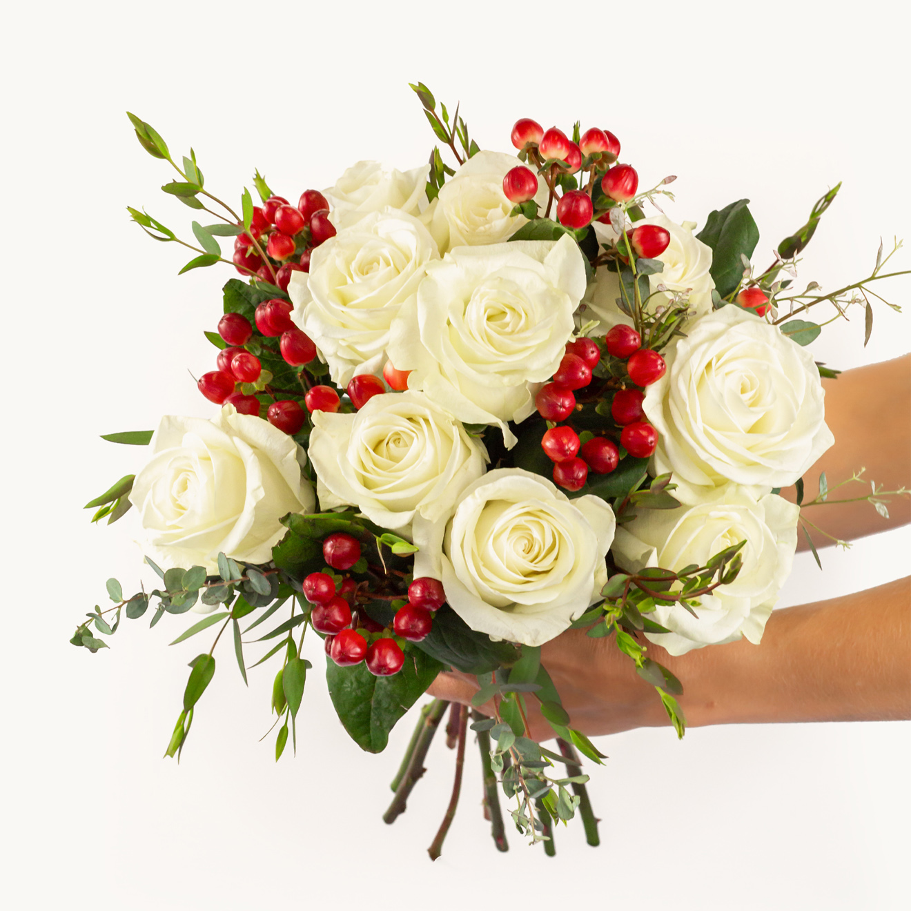 Elegant white roses paired with vibrant red berries and lush greenery, creating a stunning bouquet.