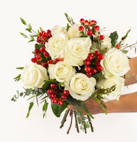 Elegant white roses paired with vibrant red berries and lush greenery, creating a stunning bouquet.