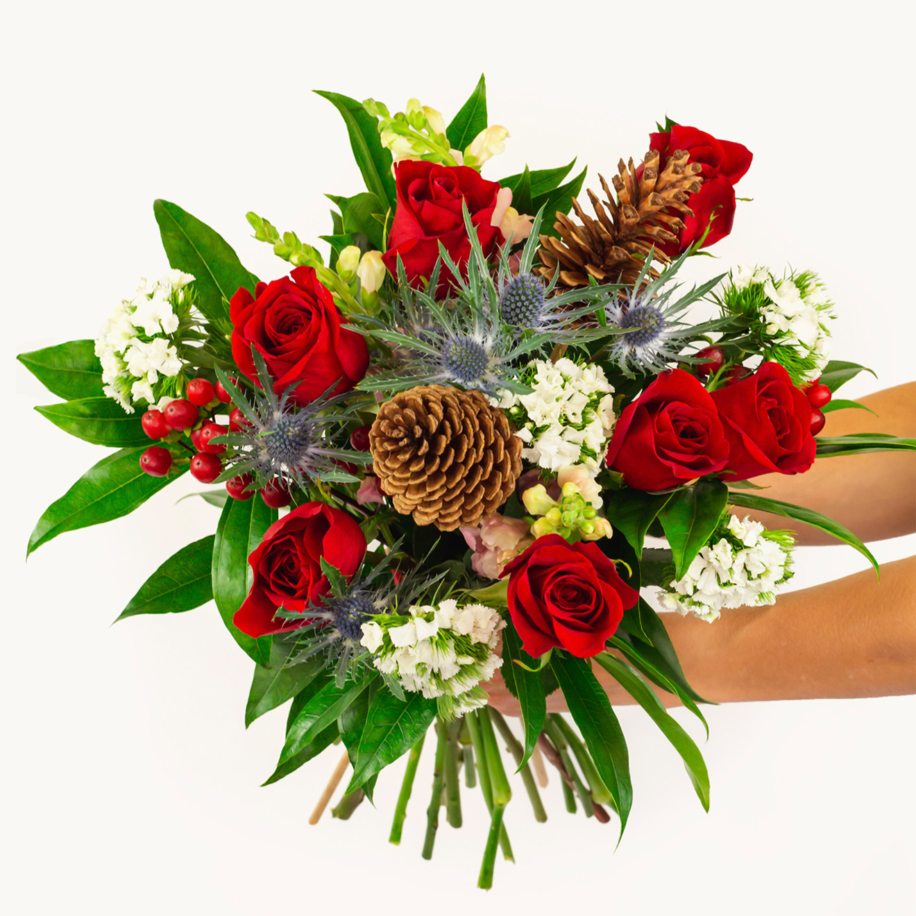 Vibrant bouquet featuring red roses, greenery, and pinecones, perfect for festive occasions.