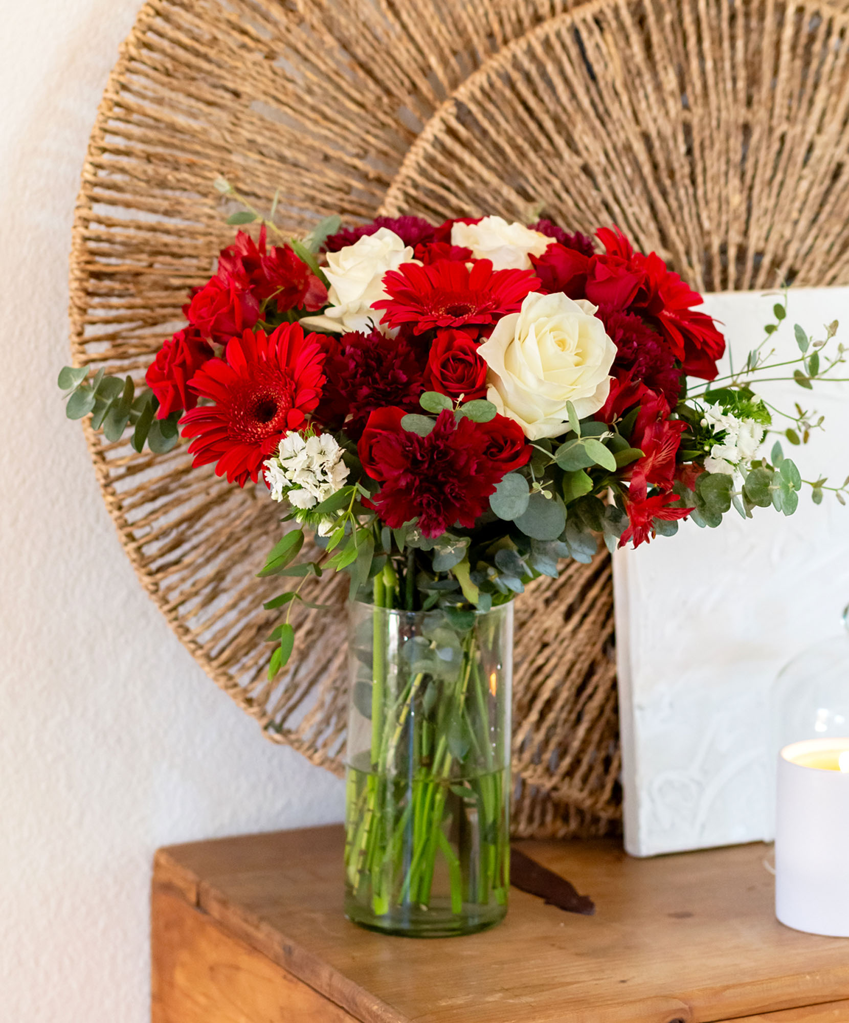 Vibrant floral arrangement featuring red gerbera daisies and white roses in a clear vase.