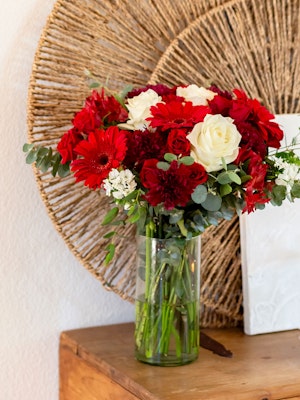 Vibrant floral arrangement featuring red gerbera daisies and white roses in a clear vase.