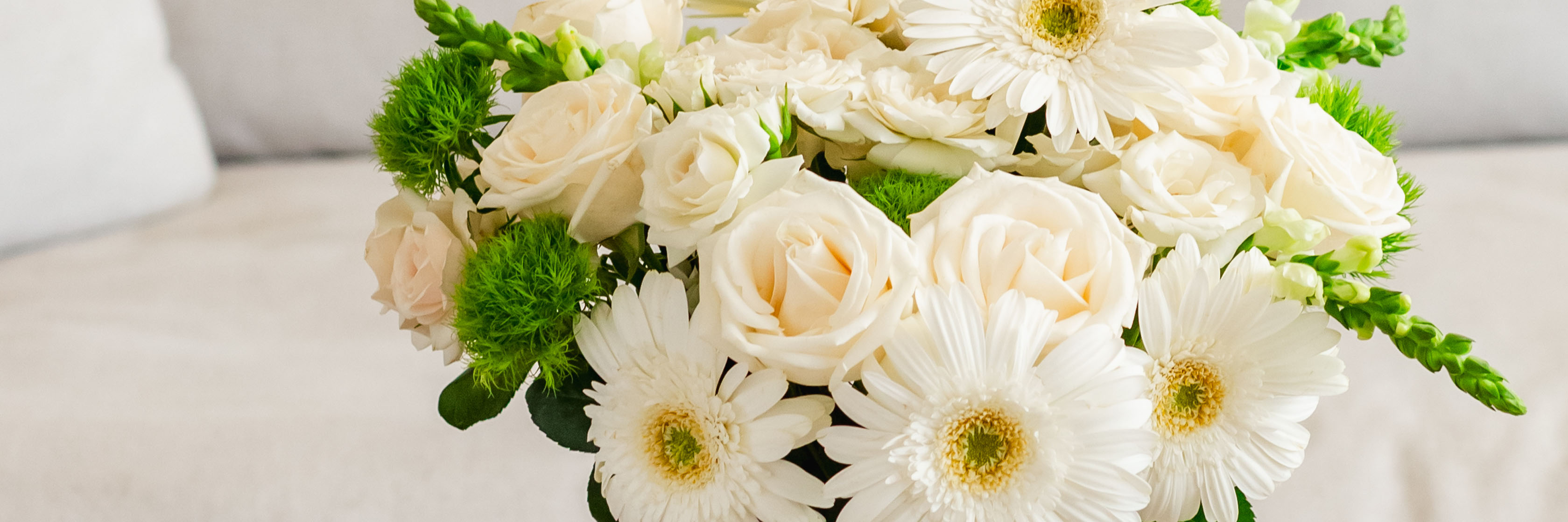 Elegant white floral arrangement featuring roses and gerbera daisies, perfect for any occasion.