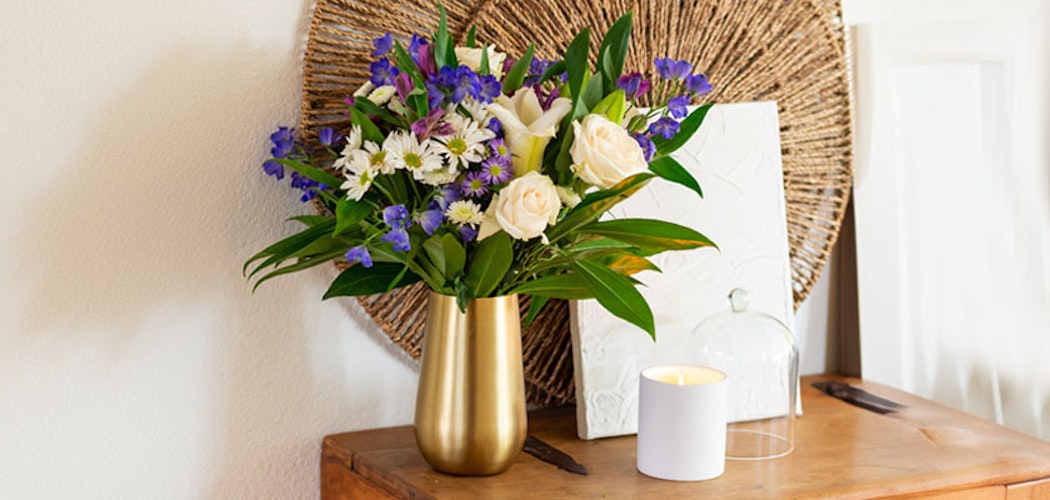 A vibrant floral arrangement featuring white roses and purple blooms in a stylish vase.