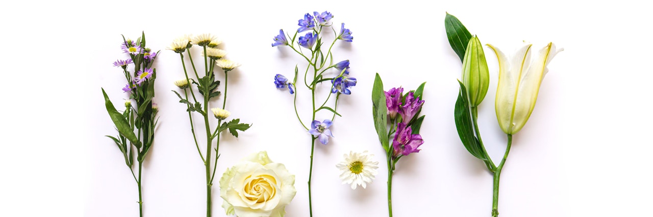 A colorful arrangement of fresh flowers including daisies, roses, and lilies on a white background.