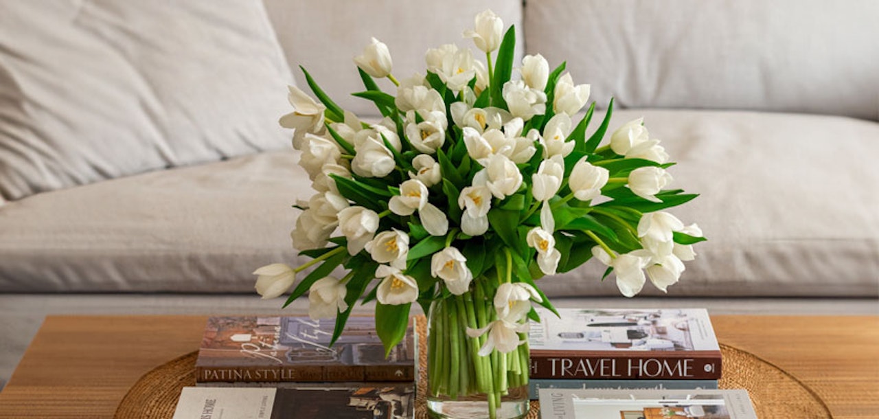 Elegant arrangement of white tulips in a glass vase, enhancing a cozy living room setting.