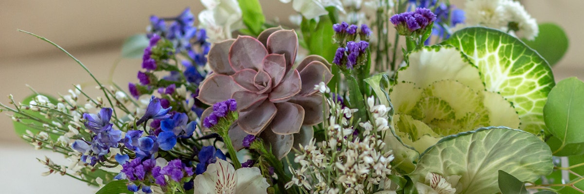 Vibrant floral arrangement featuring purple blooms, succulents, and elegant greenery.