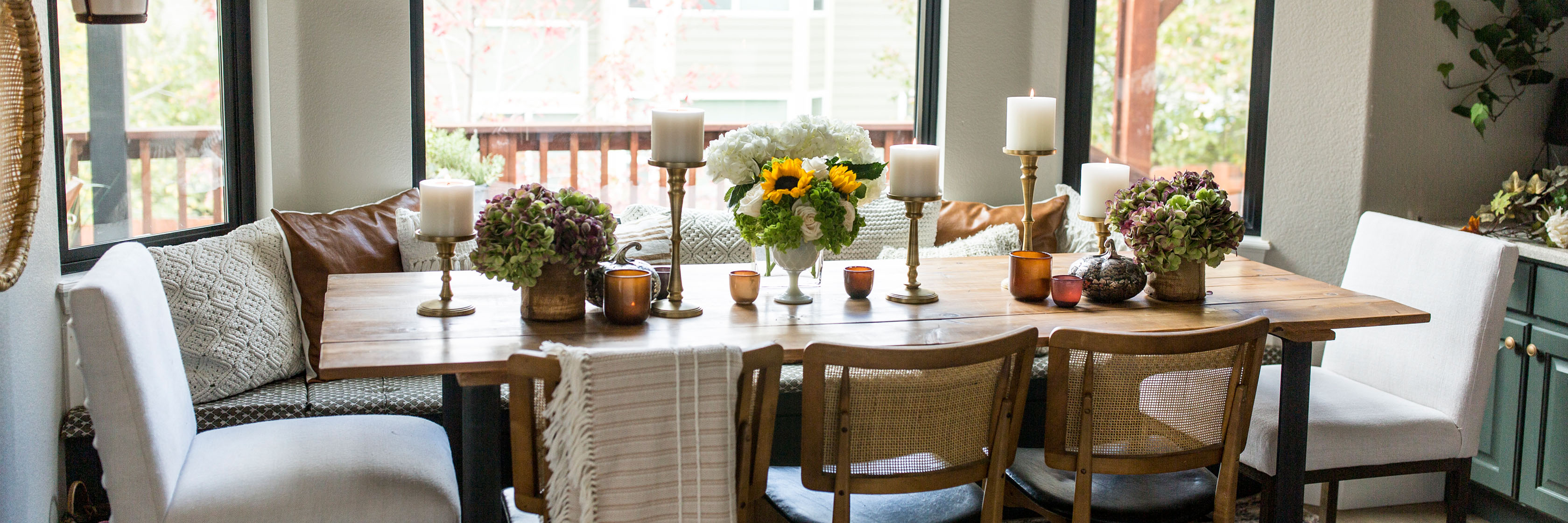 Elegant dining room featuring a rustic wooden table adorned with floral arrangements and candles.