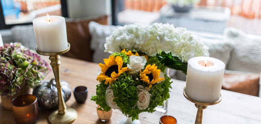 Bright floral centerpiece featuring sunflowers, roses, and elegant candles on a rustic table.